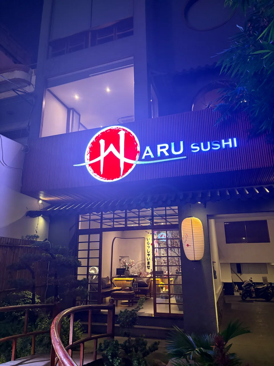 Mặt tiền Sushi Haru vào buổi tối với biển hiệu Haru Sushi sáng và lối vào có đèn lồng